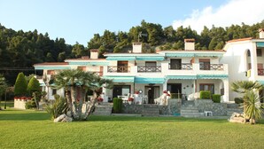 A two-story building with a balcony, a stone staircase, and a well-maintained lawn. - Triton Maisonette by RentalsPro (Fourka)