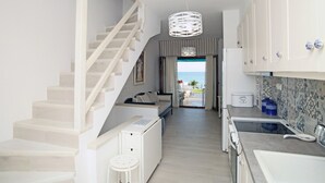A modern kitchen with a staircase, a dining area, and a view of the sea. - Triton Maisonette by RentalsPro (Fourka)