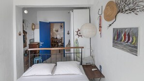 Ein Schlafzimmer mit Bett, Schreibtisch, Stuhl, einer Pendelleuchte und einem Bild an der Wand.