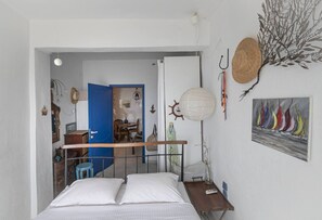 Ein Schlafzimmer mit Bett, Schreibtisch, Stuhl, einer Pendelleuchte und einem Bild an der Wand.