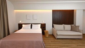 Un dormitorio con cama, sofá, mesita de noche y una lámpara de pared.