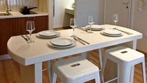 Una cocina moderna con encimeras blancas, una mesa de comedor dispuesta con platos, vasos y cubiertos.