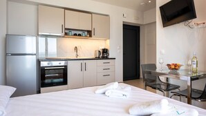 Ein modernes Hotelzimmer mit Bett, einer Küchenzeile, einem Essbereich und einem Fernseher.