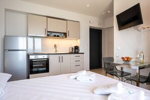 Ein modernes Hotelzimmer mit Bett, einer Küchenzeile, einem Essbereich und einem Fernseher.