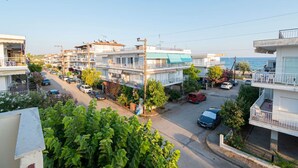 Una calle residencial con edificios de varios pisos, coches aparcados y una vista despejada del mar.