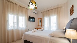 Una habitación de hotel con cama, televisor, espejo y lámpara.