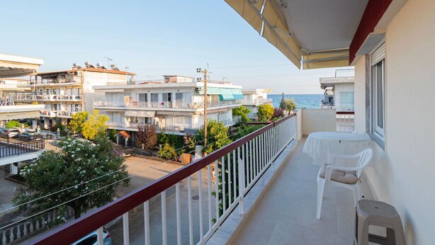 Balcón con mesa y sillas, con vistas a una zona residencial y al mar.