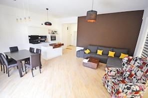 A modern living room with a dining area, a sofa set, and a kitchen in the background. - Orange Lux Apartments (Budva)