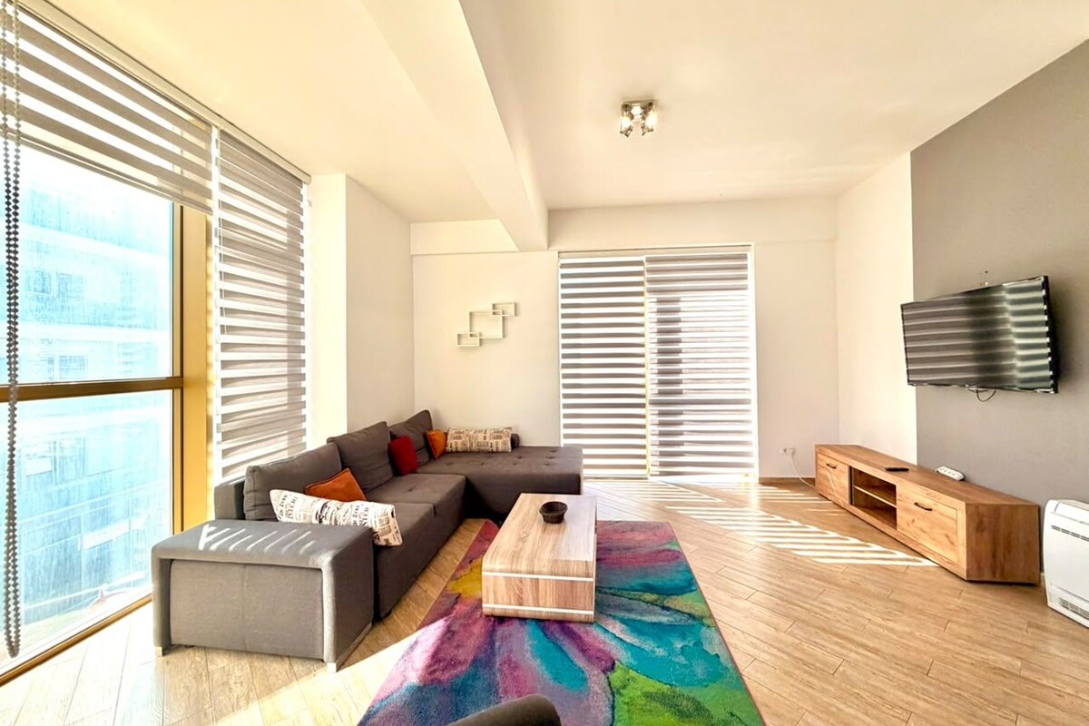 A modern living room with a sofa, coffee table, and a flat-screen TV.