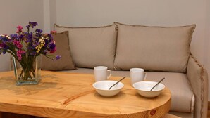 A wooden table with two white bowls and spoons, a vase with colorful flowers, and a beige sofa in the background. - Local Suite 3 - Nea Moudania (Nea Moudania)