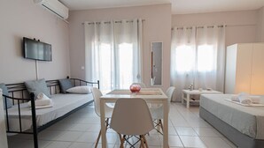 Quarto moderno e bem iluminado com uma cama, sofá, mesa de jantar e televisão.