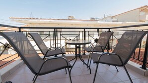 Terraço no telhado com mesa, cadeiras, guarda-corpo de vidro e vista da cidade.