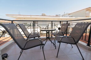 Eine Dachterrasse mit Tisch und Stühlen, einem Glasgeländer und Blick auf die Stadtlandschaft.