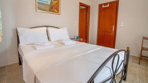 A neatly made bed with white linens and pillows, a painting of butterflies on the wall, and two wooden doors. - Azure Bay Villa by RentalsPro (Neos Marmaras)