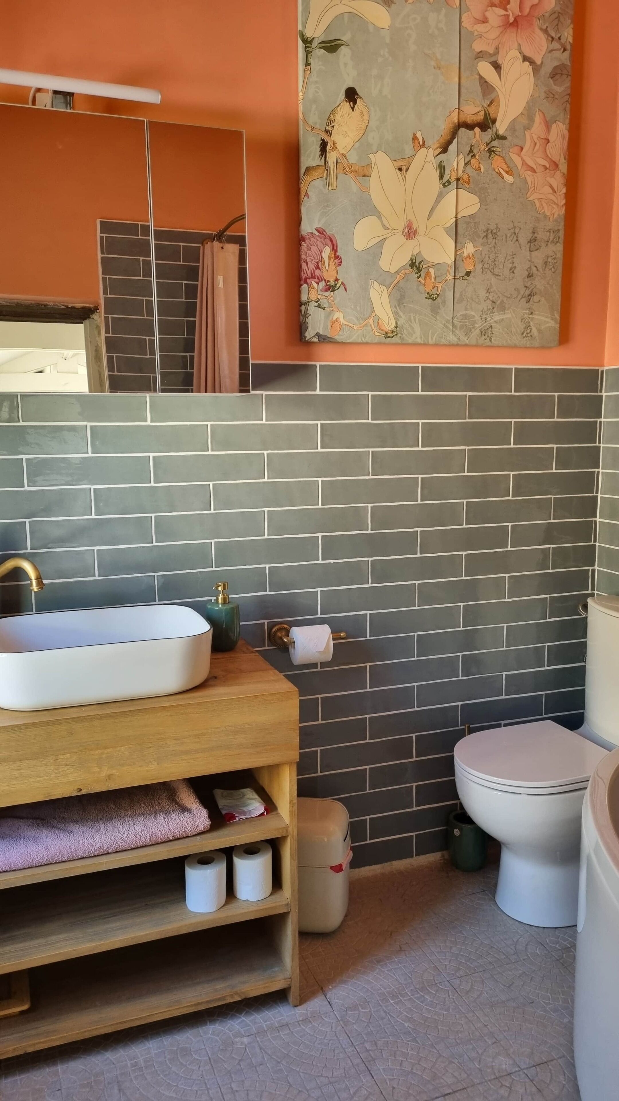 A bathroom with a white sink, a toilet, a mirror, and a decorative wall with floral patterns.