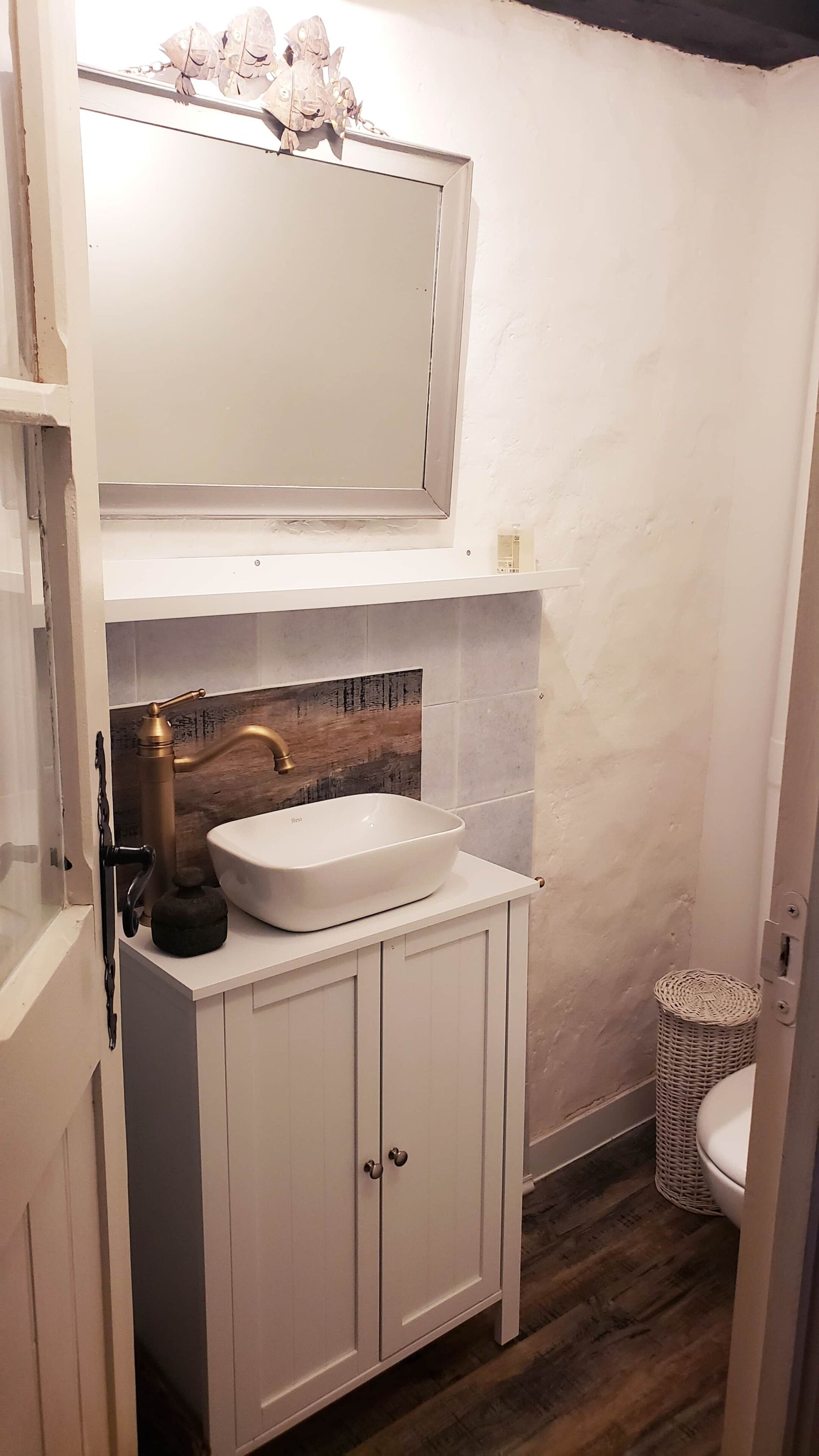 A bathroom with a white sink, a mirror above it, and a wooden backsplash.