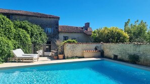 A stone building with a tiled roof, a swimming pool, and outdoor seating. - Les Chauvins ensemble (Salles-Lavalette)