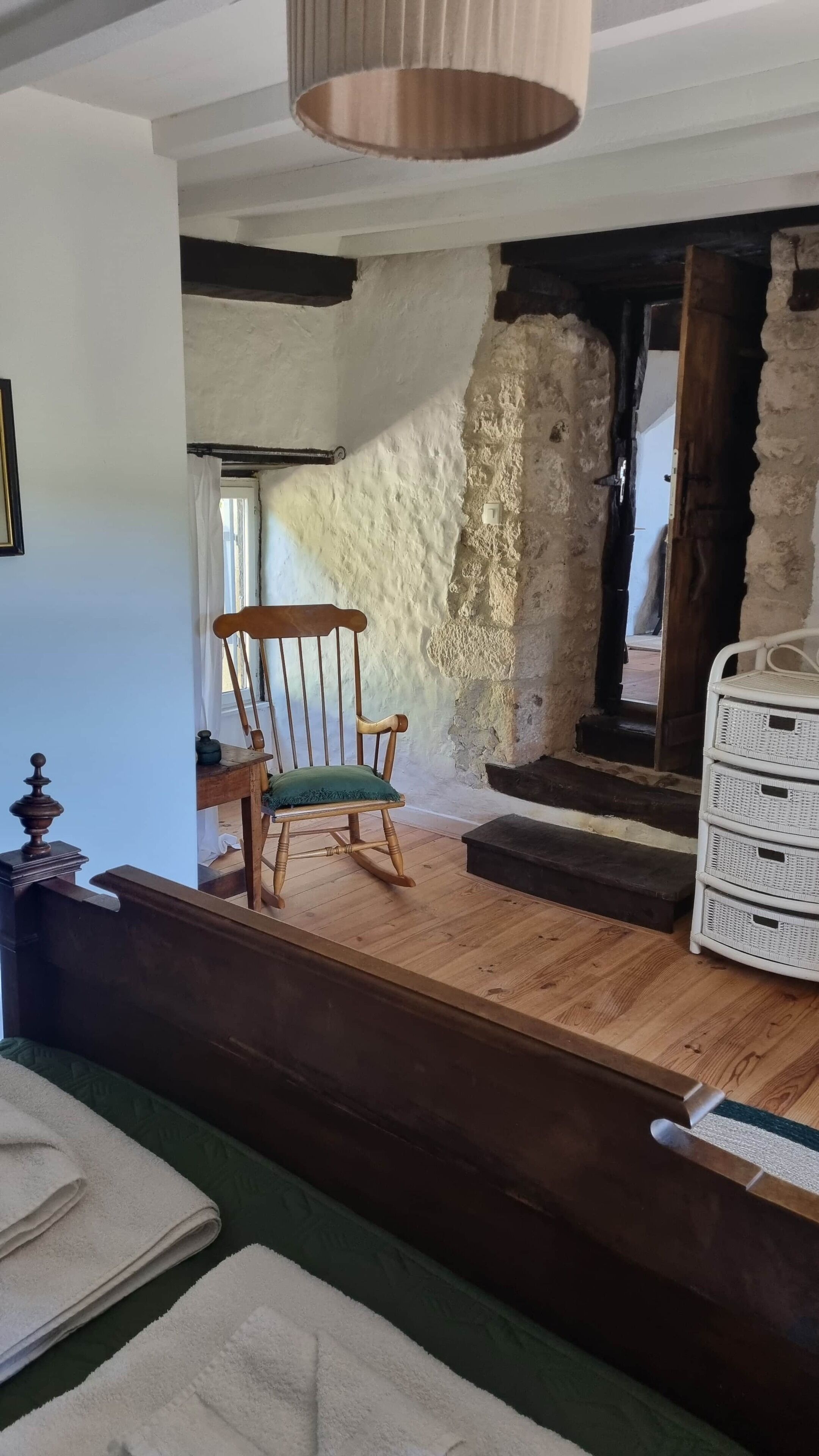 A room with a wooden chair, a white wicker basket, and a wooden table.
