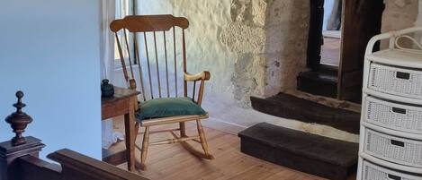 A room with a wooden chair, a white wicker basket, and a wooden table.