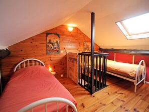 A dormitory room with two bunk beds, wooden walls, a sloped ceiling, a skylight, and a poster on the wall. - Le Gîte D'Au: Heated Pool, Spa & Fishing Pond (Saint-Amand-Magnazeix)