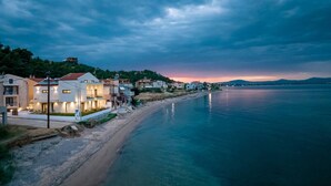 Eine Küstenstadt mit Häusern entlang der Uferlinie, einem Strand und einem Sonnenuntergang über dem Wasser.