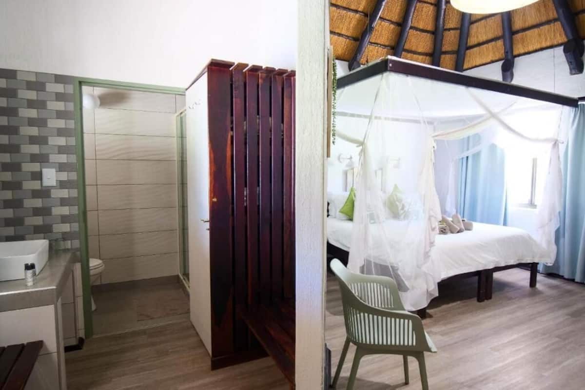 Un baño con ducha, inodoro y lavabo; un dormitorio con cama, silla y dosel; y una habitación con suelo de madera y techo inclinado.