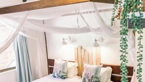 Une chambre à coucher avec un lit à baldaquin, une tête de lit en bois, des lampes de chevet et une plante suspendue.
