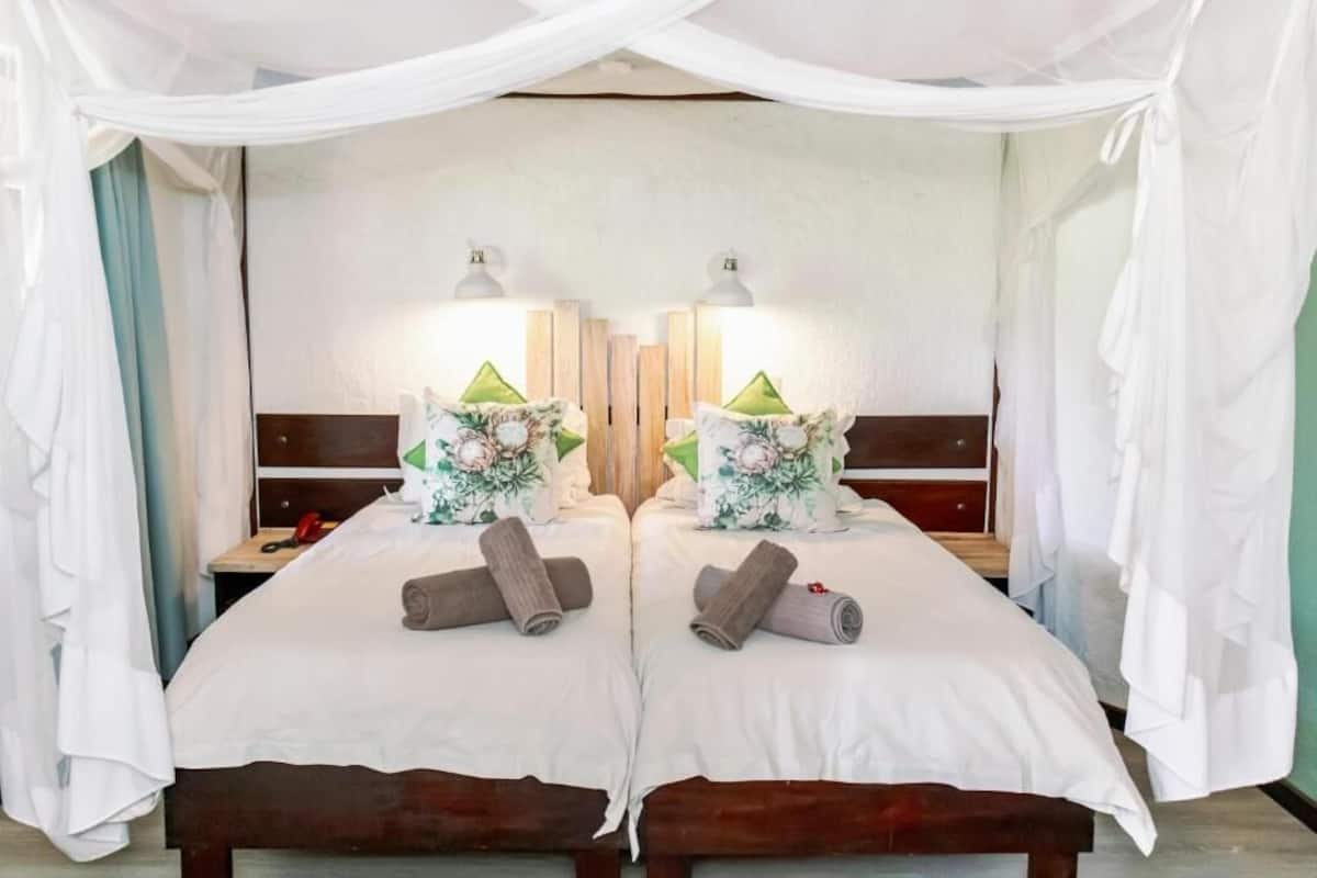 Habitación con espejo, cama, almohadas y lámparas de noche.