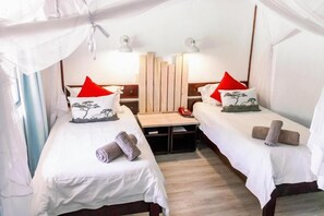 A room with two beds, each with a pillow, a bedside table, and a lamp. - Okahandja Country Hotel (Okahandja)