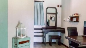 Une pièce avec un plafond en bois, un bureau, une chaise, un miroir, une petite table et un climatiseur fixé au mur.