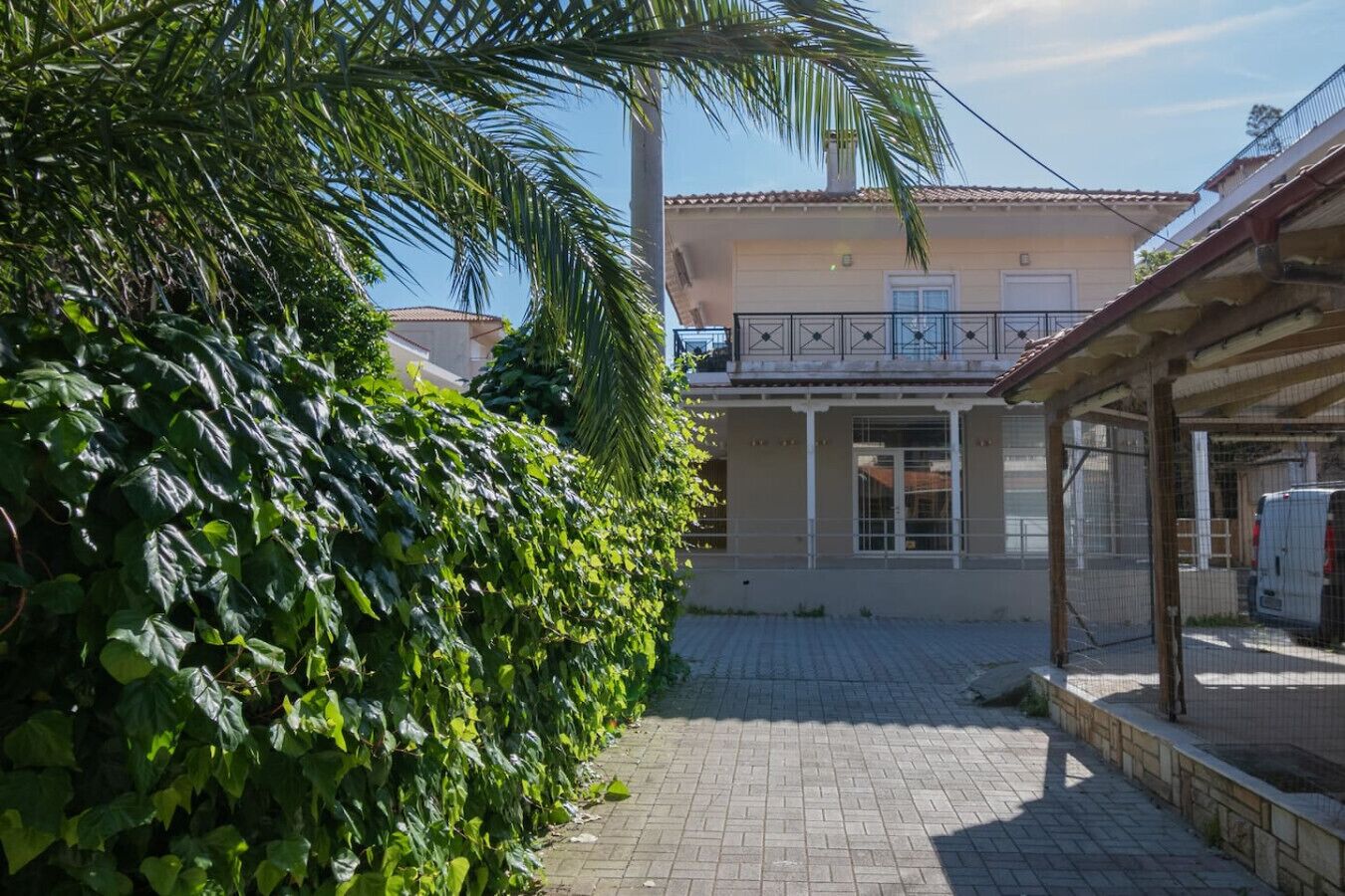 Ein Gebäude mit einem Balkon, einem gepflasterten Innenhof und einem Zaun.