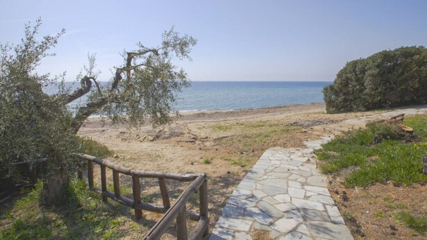 Un camí marítim que condueix a una platja, amb una tanca de fusta i escales de pedra.