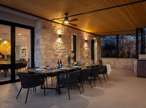 An outdoor dining area with stone walls, a wooden ceiling, and a view of trees. - Breathtaking Villa Vis (Vis)