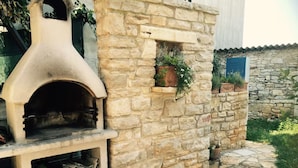 A stone building with a built-in pizza oven, a stone pathway, and potted plants. - Authentic Istrian Apartments Villa Zambratija (Umag)