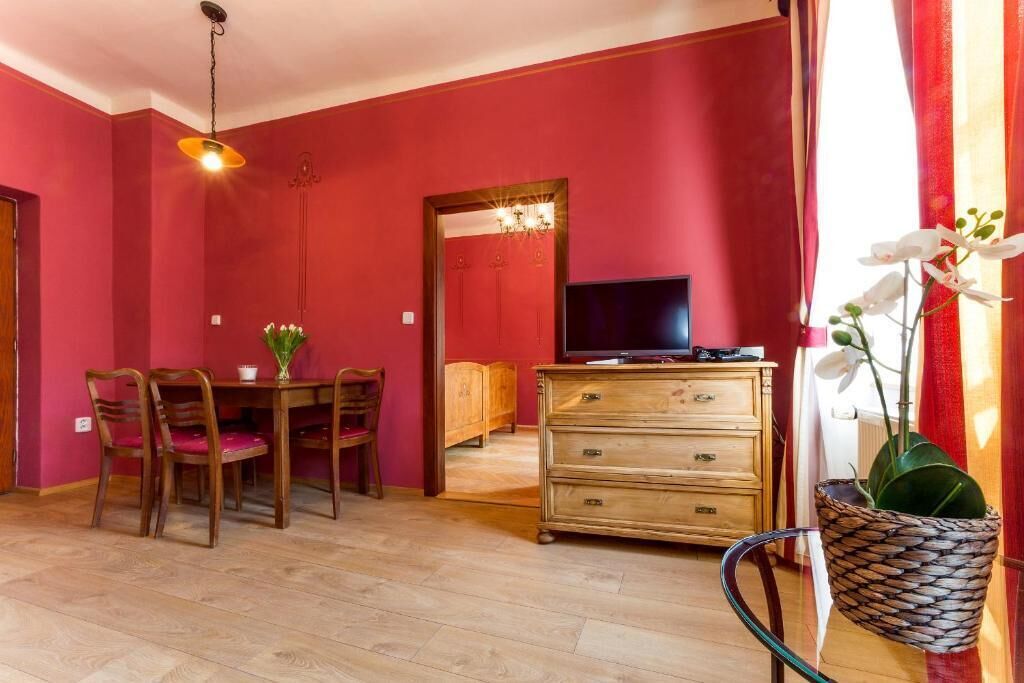 Quarto com mesa de jantar, cadeiras, televisão, cômoda e planta em vaso.