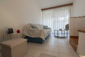 A living room with a sofa, a coffee table, a small table with a device, and a chair.