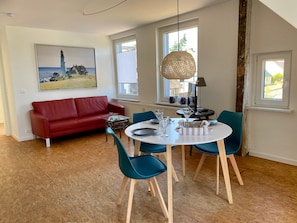 A dining area with a round table, chairs, and a red sofa.