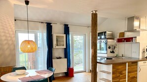 Eine moderne Küche mit einer Holzinsel, weißen Schränken und einem großen Fenster mit Vorhängen.