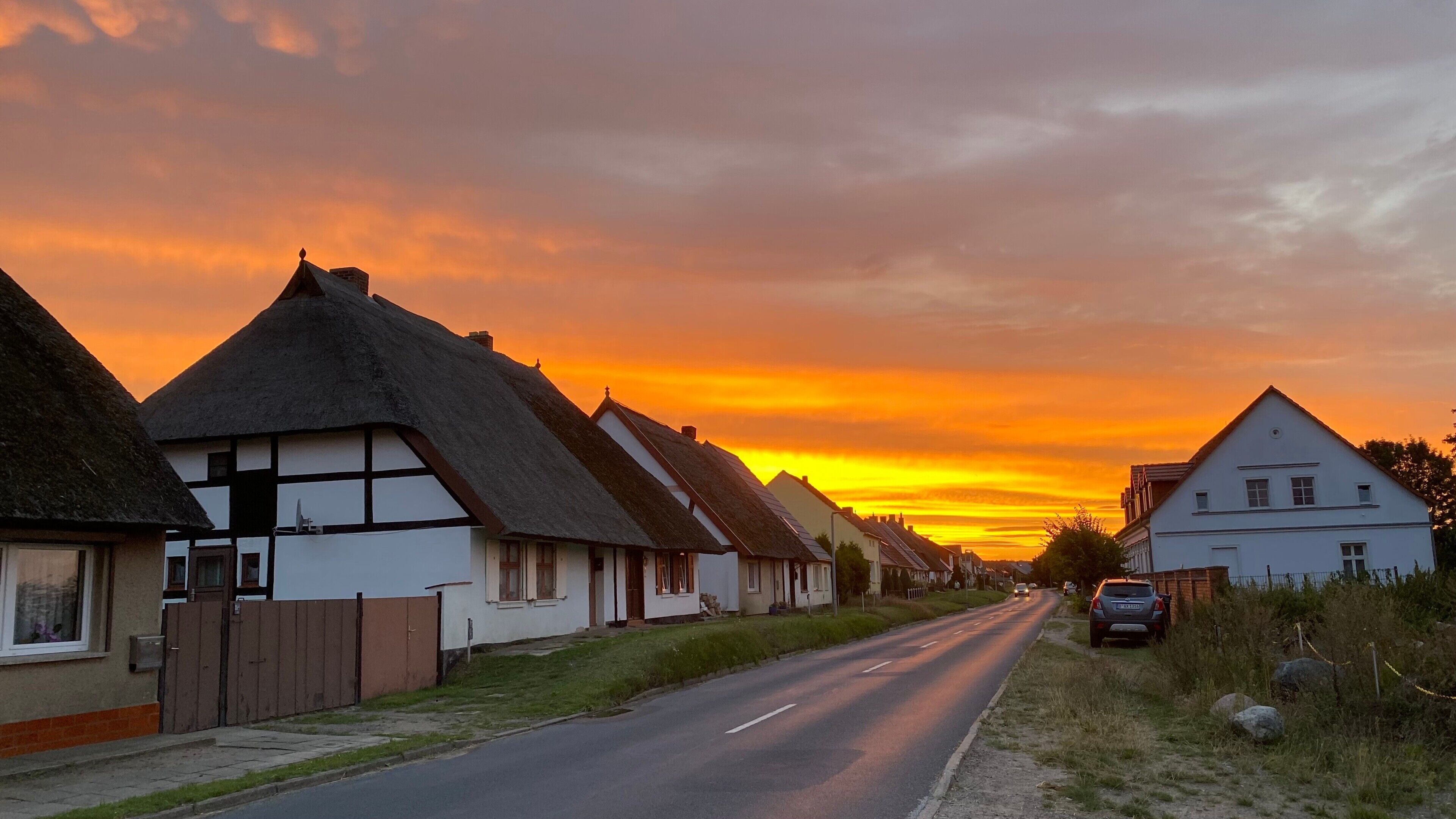 En gade med traditionelle huse, en vej og en solnedgang.