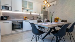 A modern kitchen with white cabinets, a microwave, an oven, and a dining area with a table and chairs.