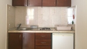 A kitchen with wooden cabinets, a sink, a stove, and a dishwasher. - Apartments Aleksić, Bečići (Bečići)