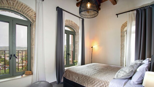 Un dormitorio con cama, lámpara, ventana con cortinas y vistas al exterior.