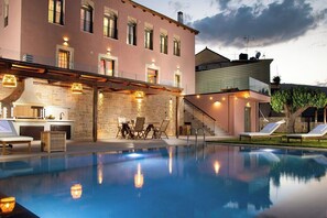 A swimming pool with lounge chairs and a bar area, surrounded by a building with multiple windows and a staircase. - Vineyard View, next to Best Wineries, "Trigos" appartment (52QJ+W6 Avgeniki)