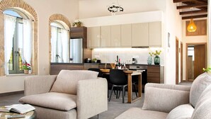 Una sala de estar moderna con sofá, una mesa de comedor y una zona de cocina con armarios y un refrigerador.
