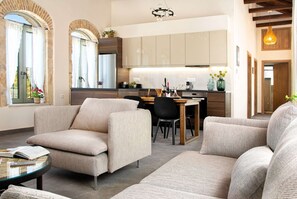 Ein modernes Wohnzimmer mit einer Couch, einem Esstisch und einer Küchenzeile mit Schränken und einem Kühlschrank.