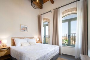 Ein Schlafzimmer mit Bett, Nachttischen, einer Lampe, einem Bild an der Wand und einem Fenster mit Vorhängen.