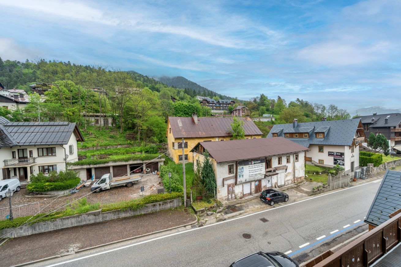 A residential area with houses, a road, and a hilly landscape in the background.