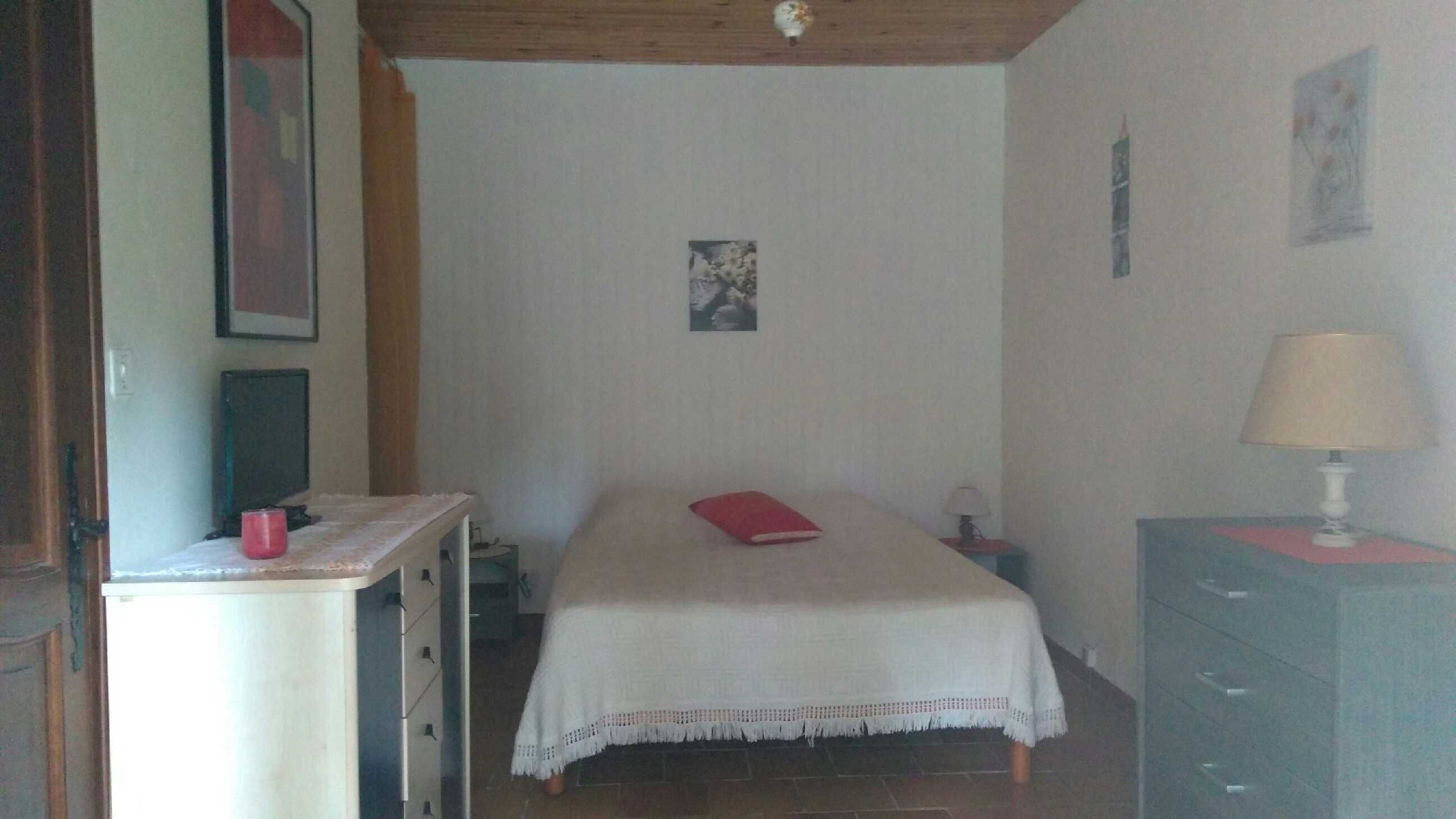 A bedroom with a bed, a nightstand, a dresser, a lamp, and a picture on the wall.
