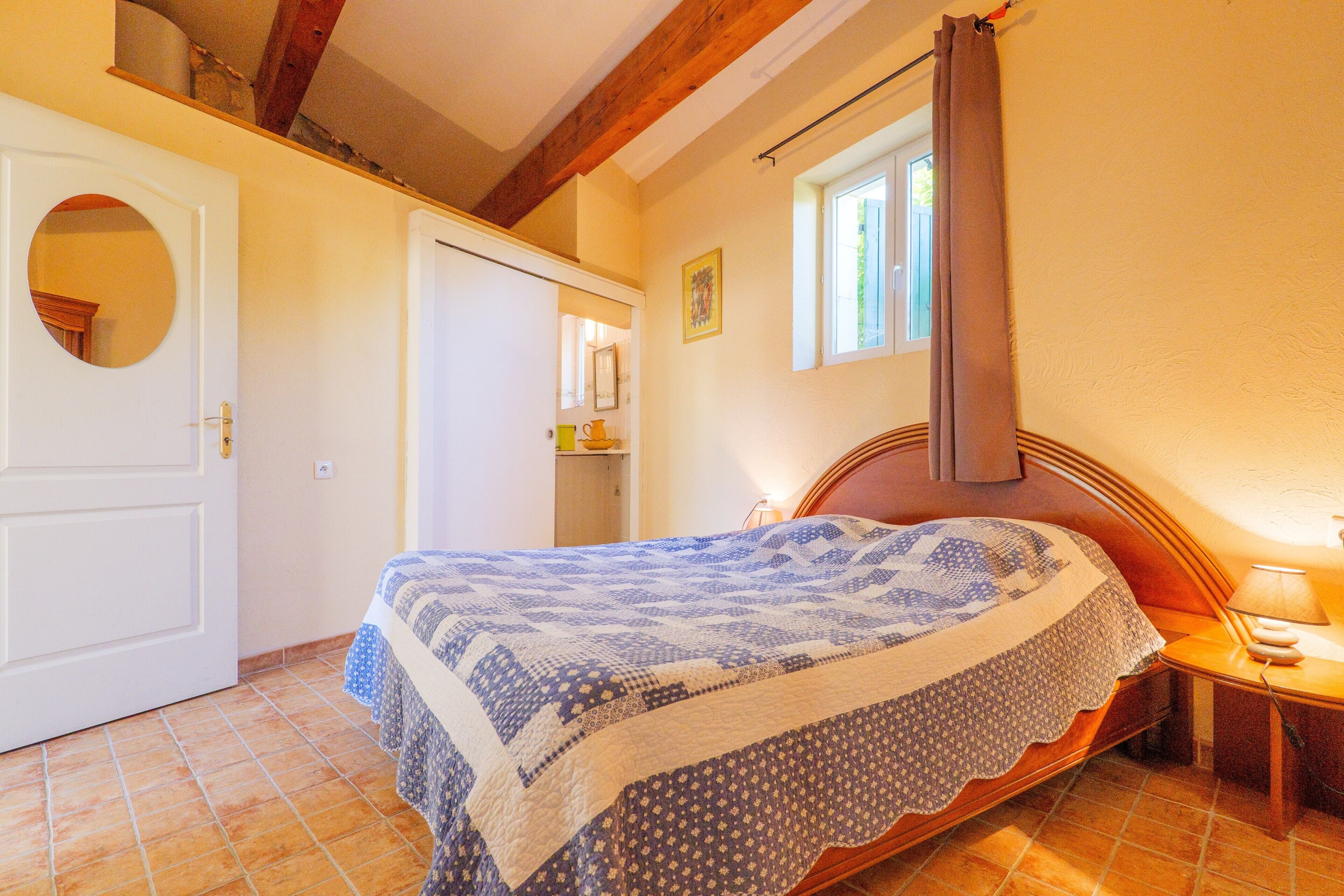 Une chambre à coucher avec un lit, une fenêtre, une porte et un miroir.