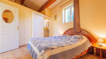 Une chambre à coucher avec un lit, une fenêtre, une porte et un miroir.